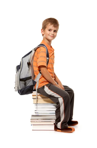 Kitaplar üzerinde oturan bir okul çocuğu — Stok fotoğraf