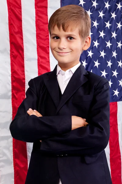 Portait de menino caucasiano com bandeira americana no fundo . — Fotografia de Stock