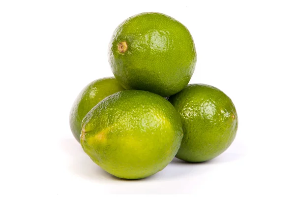 Gruppe von ganzen Limetten und einer halben Limette auf Weiß — Stockfoto