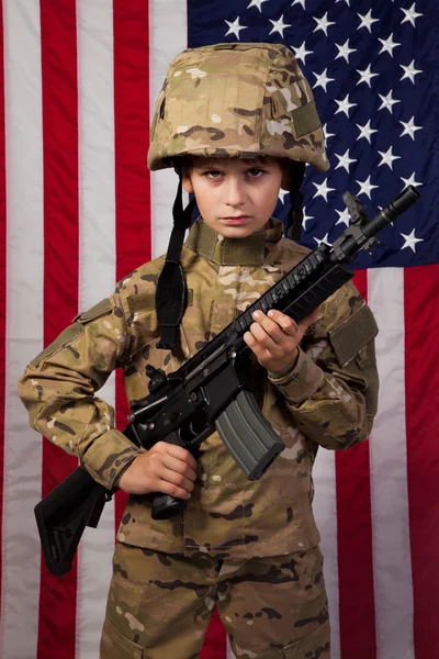 少年アメリカ兵小銃とアメリカの国旗の前で — ストック写真