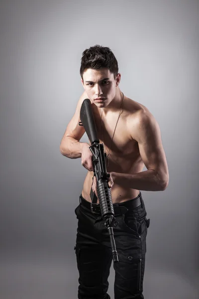 Knappe ontbloot bovenlijf soldaat houdt een geweer — Stockfoto
