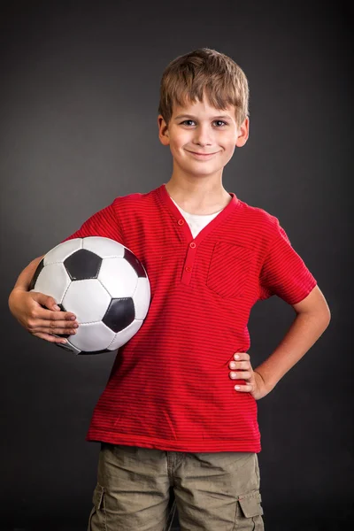 Un mignon garçon tient un ballon de football. Balle de football — Photo