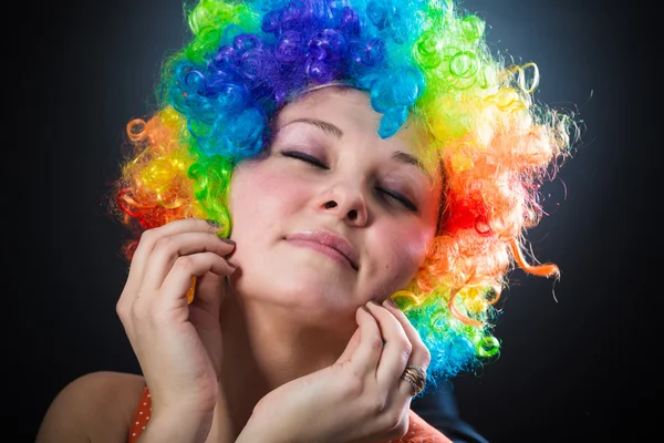 Kvinna i clownen peruk leende drar falska hår på sidorna — Stockfoto