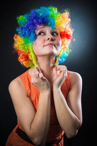 Mujer con peluca de payaso sonriendo tirando de pelo falso en los lados — Foto de Stock