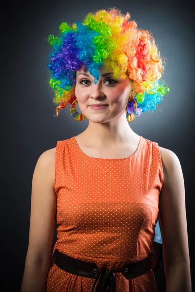 Mujer con peluca de payaso sonriendo tirando de pelo falso en los lados — Foto de Stock