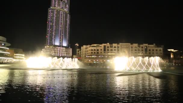 Fountain near Burj Khalifa illuminated by the city at night — Stock Video