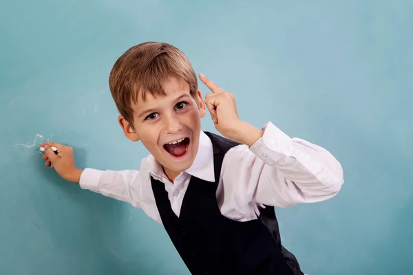 Skolan student skriver på svarta tavlan i skolan — Stockfoto