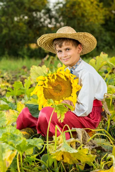 Young happy boy hold sunflower in a garden — Stock Photo, Image