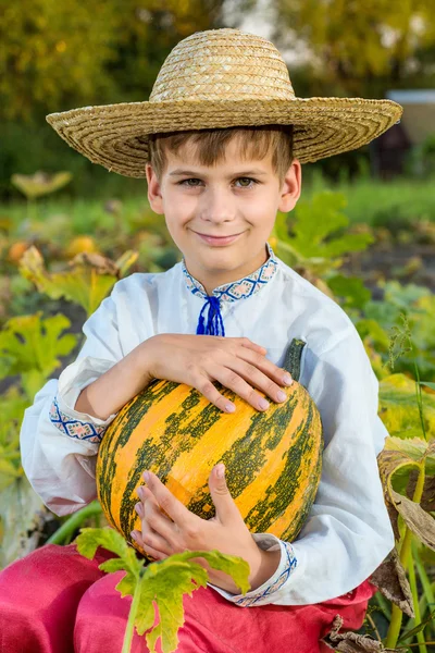 Leende pojke håller stora gul pumpa i händer — Stockfoto