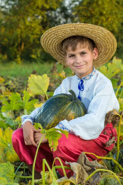Sorrindo menino segurando grande abóbora amarela nas mãos — Fotografia de Stock