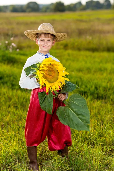 Il ragazzo felice tiene il girasole in un giardino — Foto Stock