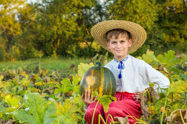 Smiling boy holding big yellow pumpkin in hands — Stock Photo, Image