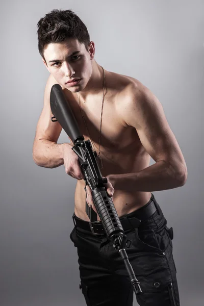 Handsome soldier is holding a rifle — Stock Photo, Image