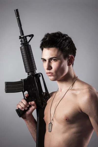 Handsome soldier is holding a rifle — Stock Photo, Image