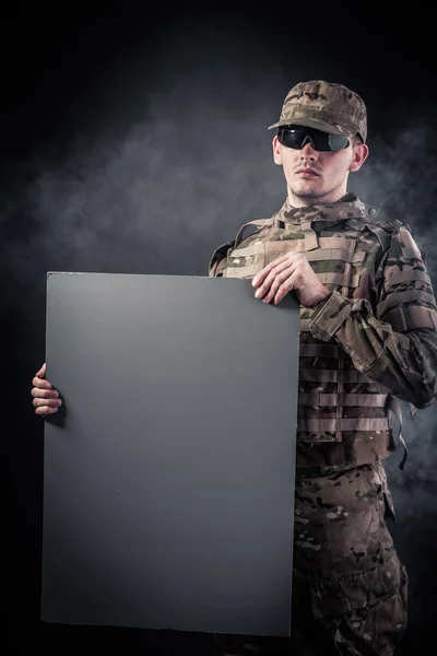 Soldado moderno está segurando um pôster — Fotografia de Stock