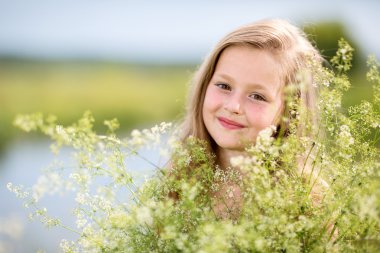 The little girl is stanging in the grass and holding a bouquet clipart
