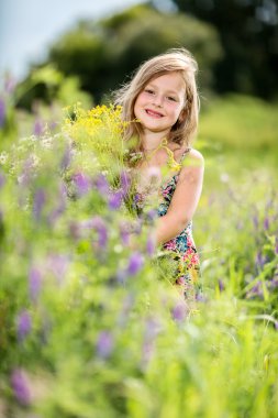 The little girl is stanging in the grass and holding a bouquet clipart