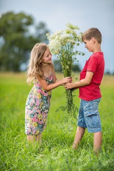 Våren. Pojke ger flickan en bukett blommor . — Stockfoto