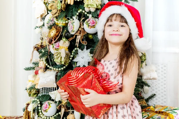 Glückliches kleines Mädchen mit Weihnachtsgeschenk lächelnd — Stockfoto
