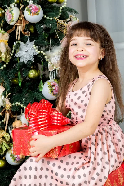Счастливая маленькая девочка с рождественским подарком улыбается — стоковое фото