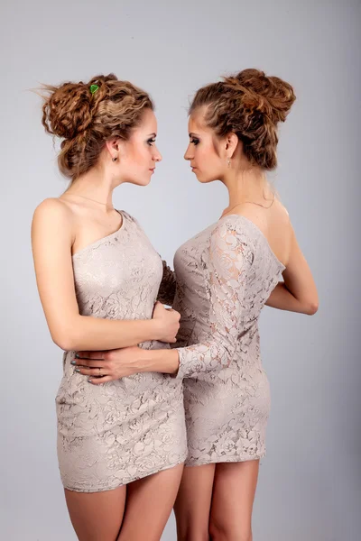 Duas meninas gêmeas, isoladas no fundo cinza — Fotografia de Stock