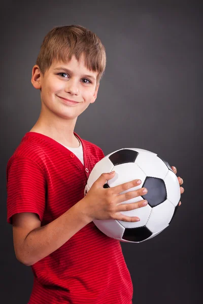 Menino está segurando uma bola de futebol — Fotografia de Stock