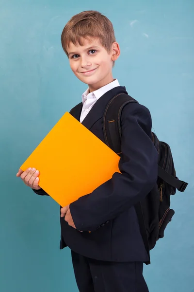 Skolpojke håller en orange bok — Stockfoto