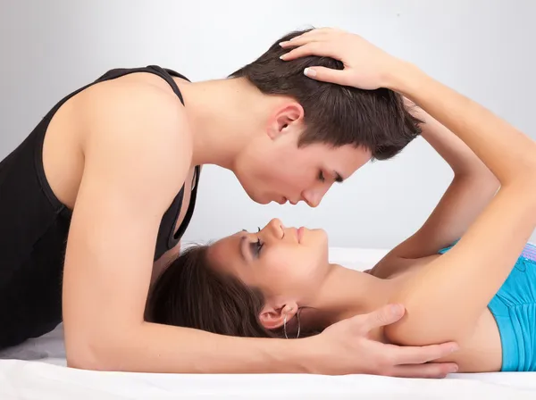 Mladá žena líbat muž na posteli — Stock fotografie