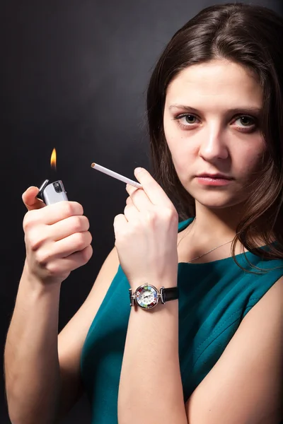 Mooie jonge vrouw is roken sigaretten op zwarte achtergrond — Stockfoto