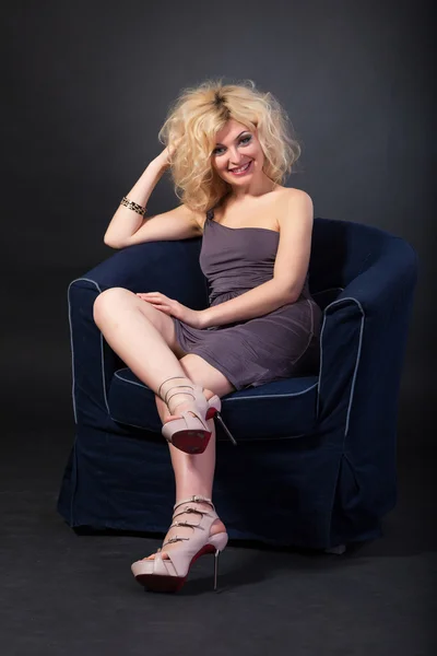 Blonde woman sitting in a navy armchair — Stock Photo, Image