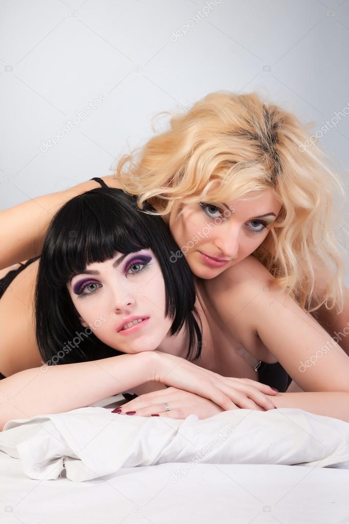 Two attractive lesbians are hugging lying on bed