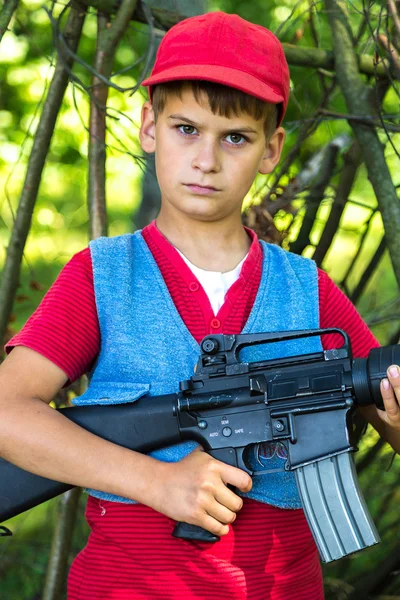 Boy holding a gun in the field. — Stock Photo, Image