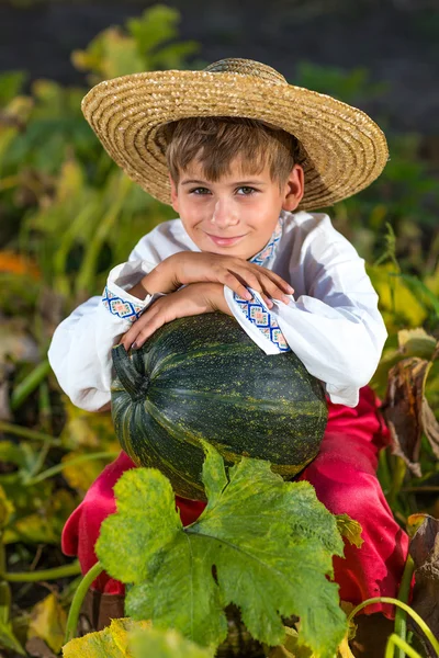 Smiling boy holding  big yellow pumpkin in hands — Stock Photo, Image