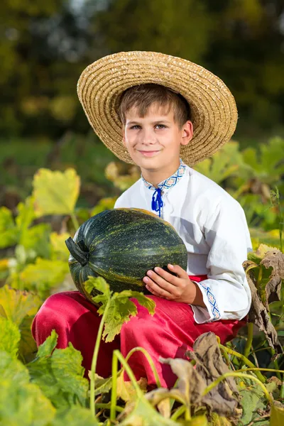 Smiling boy holding  big yellow pumpkin in hands — Stock Photo, Image