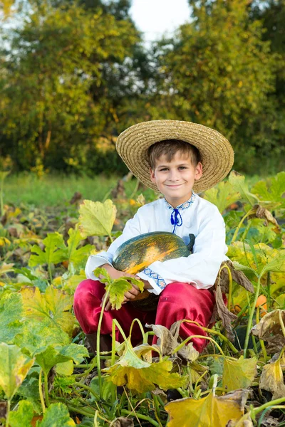 Garçon souriant tenant une grosse citrouille jaune dans les mains — Photo