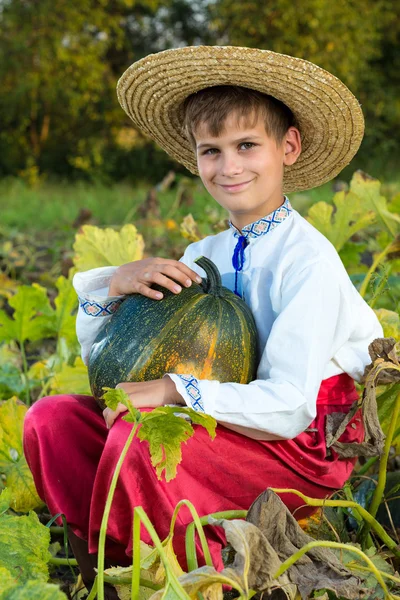 Улыбающийся мальчик держит в руках большую желтую тыкву. — стоковое фото