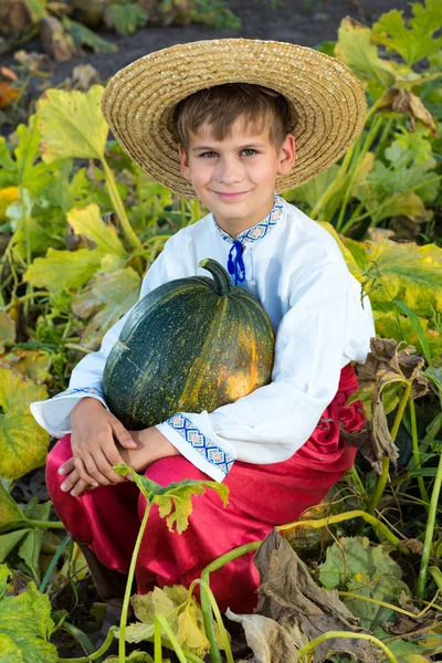 Smiling boy holding  big yellow pumpkin in hands — Stock Photo, Image