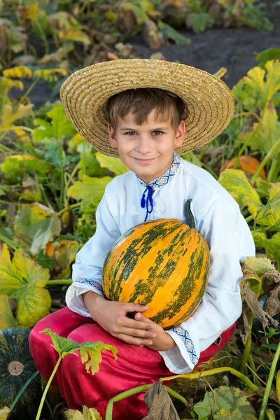 मुस्कुराते हुए लड़का हाथों में बड़ा पीला कद्दू पकड़े हुए — स्टॉक फ़ोटो, इमेज