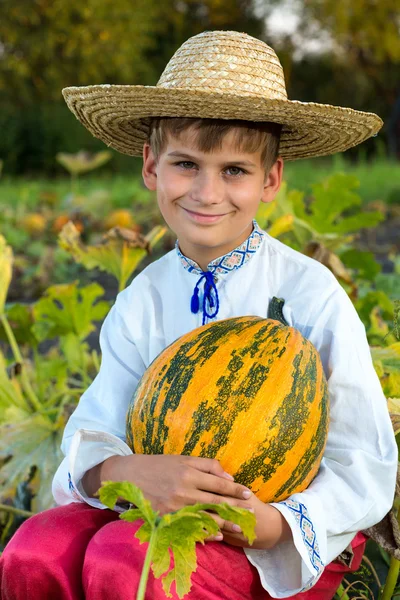 Lachende jongen bedrijf grote gele pompoen in handen — Stockfoto