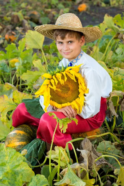 Kleiner glücklicher Junge hält Sonnenblume in einem Garten — Stockfoto