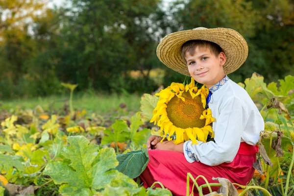 Šťastný chlapec drží slunečnice v zahradě — Stock fotografie