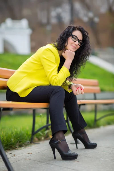 Beautiful girl is sitting on a park bench — Stock Photo, Image