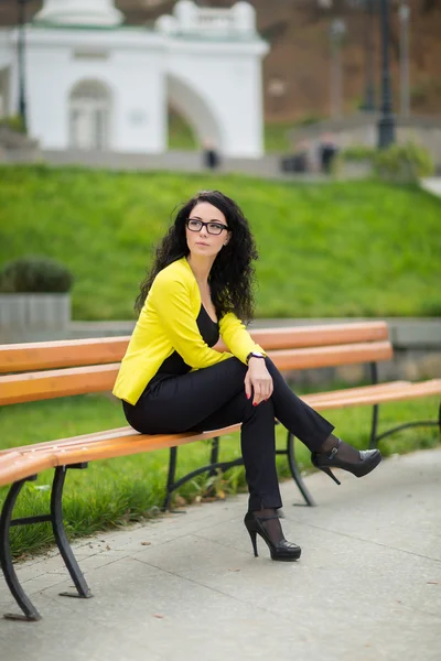 Vrij triest jonge vrouw met lang krullend haar zit in het park — Stockfoto