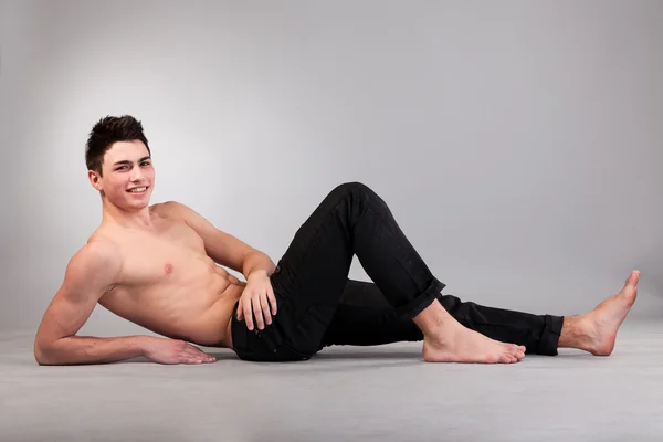 Gesunder muskulöser junger Mann auf grauem Hintergrund — Stockfoto