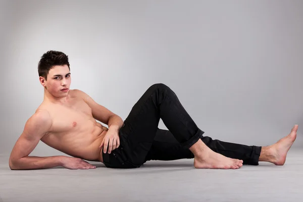 Zdrowe mięśni młody człowiek na szarym tle — Zdjęcie stockowe