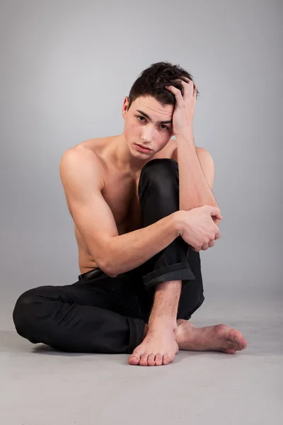 Здоровий м'язистий молодий чоловік на сірому фоні — стокове фото