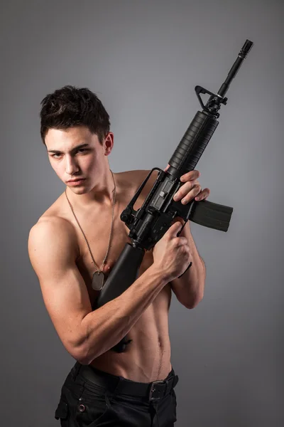Handsome bare-chested soldier is holding a rifle — Stock Photo, Image