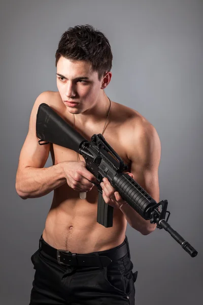 Yakışıklı çıplak göğüslü asker tüfeği tutan — Stok fotoğraf