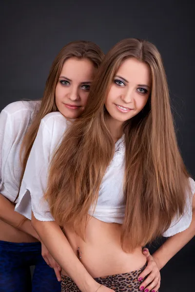 Två vackra flickor tvillingar, isolerade på svart — Stockfoto