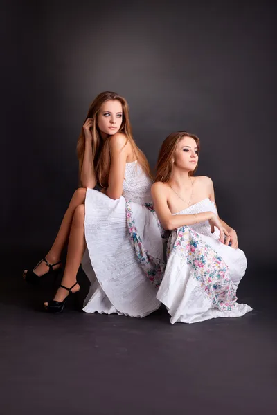 Две девочки-близнецы, изолированные на черном фоне — стоковое фото
